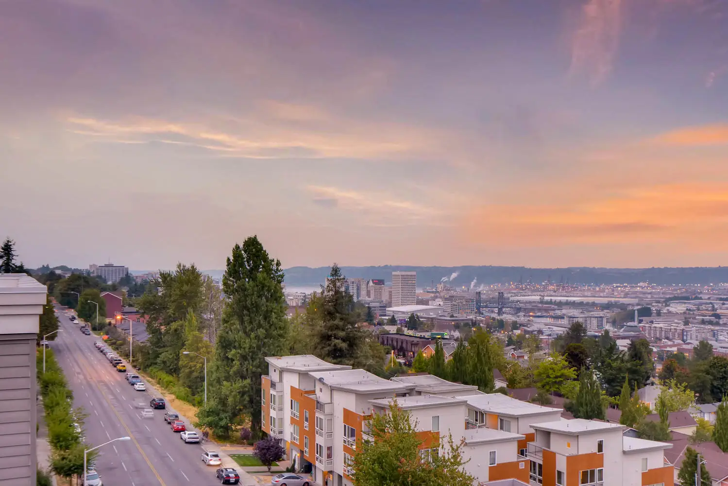 Skyline of Tacoma Washington, lots of trees and buildings, mountains in the distance